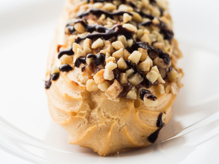 chocolate eclair sprinkled with nuts on a white plate