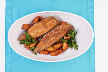 Grilled fish steak is served in batter with braised and roasted potato wedges. Mediterranean cuisine, European dish