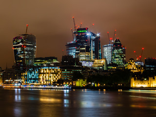 Fototapeta na wymiar Skyline of London with its famous skyscrapers and in the foreground the Thames at night