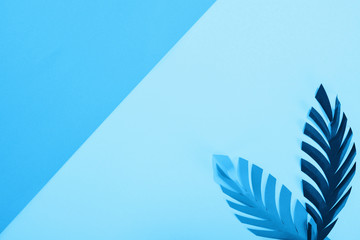 top view of paper leaves on blue minimalistic background with copy space