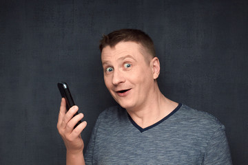 Portrait of happy and surprised man holding phone