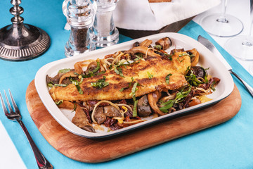Seafood, Mediterranean cuisine. Grilled fish steak with mushrooms, oyster mushrooms, boletus, greens and onion rings. Caucasian kitchen