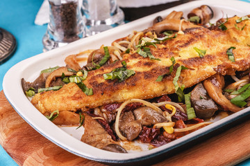 Seafood, Mediterranean cuisine. Grilled fish steak with mushrooms, oyster mushrooms, boletus, greens and onion rings. Caucasian kitchen