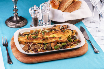 Seafood, Mediterranean cuisine. Grilled fish steak with mushrooms, oyster mushrooms, boletus, greens and onion rings. Caucasian kitchen