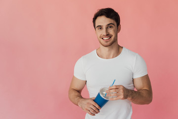 muscular man in white t-shirt holding beverage isolated on pink