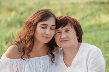 Fototapeta premium Mom and daughter are sitting on the grass enjoying a walk