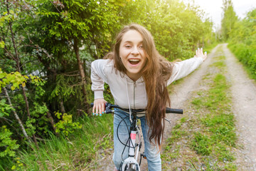 Young woman riding bicycle in summer city park outdoors. Active people. Hipster girl relax and rider bike. Cycling to work at summer day. Bicycle and ecology lifestyle concept