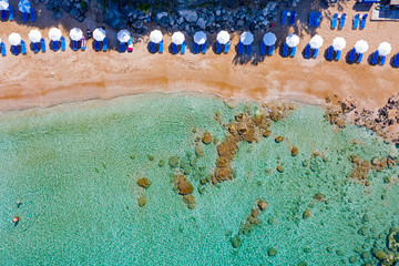 Aerial view of sandy beach with umbrellas and sun beds. Beautiful coastline on a sunny summer day.