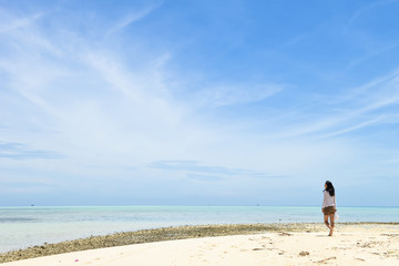 single young Asian girl walking on tropical white sand beach, at Pulau Sibuan, Semporna, Sabah, Malaysia