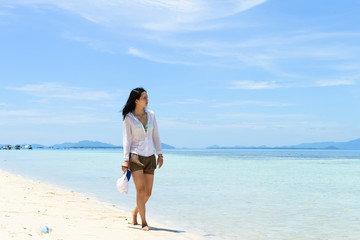 Fototapeta na wymiar single young Asian girl walking on tropical white sand beach, at Pulau Sibuan, Semporna, Sabah, Malaysia