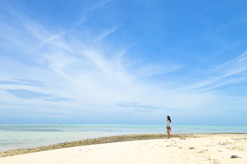 Fototapeta na wymiar single young Asian girl walking on tropical white sand beach, at Pulau Sibuan, Semporna, Sabah, Malaysia