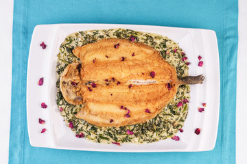 Fried steak of sea fish in batter, in a creamy sauce with greens and rose petals. Caucasian cuisine, Mediterranean food