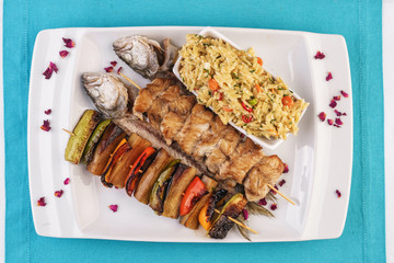 Mediterranean dish, Georgian recipe. Baked chicken skewers with lemon, vegetables, pepper, zucchini, eggplants and grilled tomatoes with spices, and steamed rice