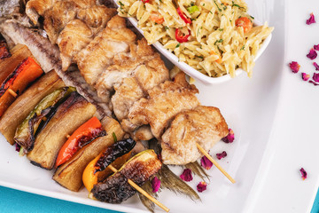 Mediterranean dish, Georgian recipe. Baked chicken skewers with lemon, vegetables, pepper, zucchini, eggplants and grilled tomatoes with spices, and steamed rice