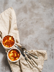 Flat lay of prepared apple cakes, tarts, puddings in a porcelain baking dish on a gray concrete...