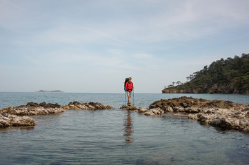 Fototapeta na wymiar Woman with backpack trekking on a sea coast