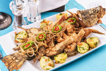 Seafood, Mediterranean cuisine. Baked fish with potatoes, onion rings, chili pepper, lemon and greens. Caucasian kitchen