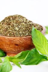 dried mint powder and natural green leaves of this plant in wooden plate