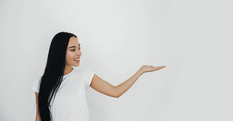 Brunette woman advertising product pointing hand into copy space background.