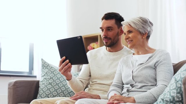 family, generation and people concept - happy smiling senior mother and adult son having video chat on tablet computer at home