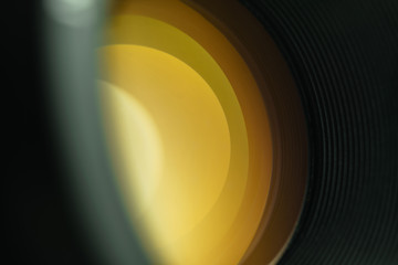 Beautiful camera lens  with yellow light of glass on a black background.