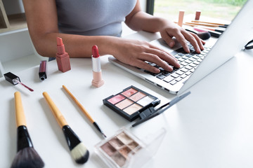 woman blogger present cosmetic product sitting in front tablet and broadcast to social network by...