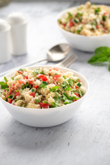 Tabbouleh - Arabian vegetarian salad made of couscous, tomatoes, cucumbers, parsley, onions and lemon juice. Couscous with vegetables in a white bowl on the table.