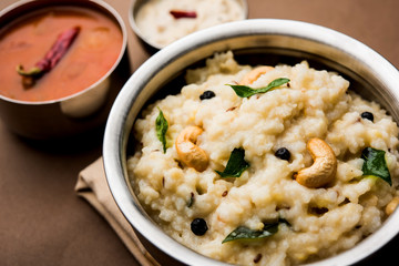 Ven pongal recipe is a popular South Indian food prepared with rice & moong dal and served with sambar and coconut chutney, selective focus