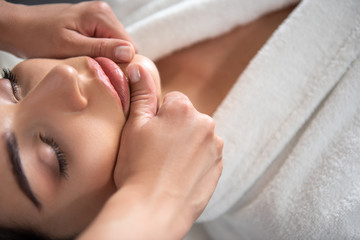 Obraz na płótnie Canvas Beautiful young woman receiving face massage at beauty salon