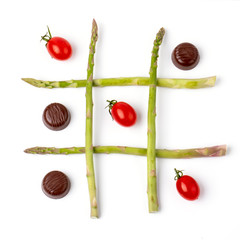 tic tac toe made with cherry tomatoes, chocolate and asparagus. Metaphor concept of healthy food,...