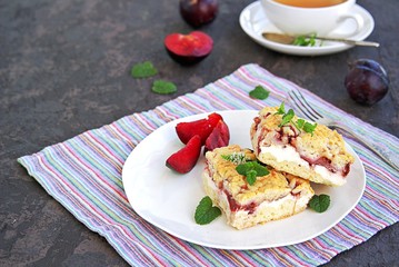 Sliced shortbread cake with curd cream and plum on a white plate. Sweet cakes. Harvest plums.
