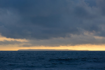 Naklejka na ściany i meble Lundy Island at sunset with stormy sky