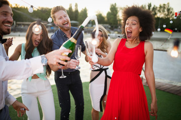 Group of friends drinking, chatting and having a fun at outdoor party