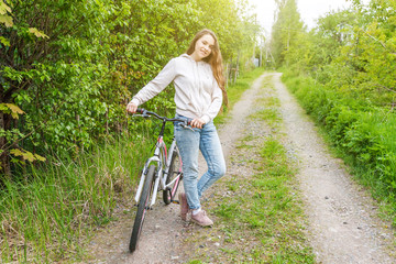 Naklejka premium Young woman riding bicycle in summer city park outdoors. Active people. Hipster girl relax and rider bike. Cycling to work at summer day. Bicycle and ecology lifestyle concept