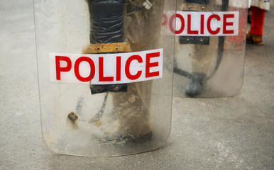 Indian police officers stand and  hold  sticks and transparent shields to stop  regulate protests,procession and movement of people on the road