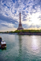 The Eiffel Tower across the Seine River in Paris, France on a sunny day with beautiful clouds.