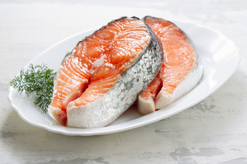 fresh salmon with herbs on white dish on ceramic background
