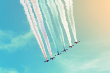 Group of aircraft flies in a row leaving a smoky trail in the sky.