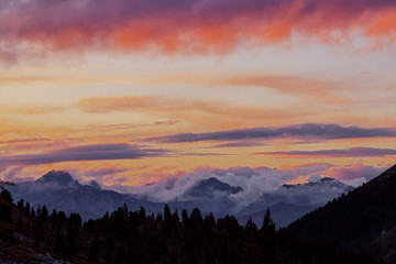 Panorama silhouette forest and mountain tops in red orange blue clouds gradient sunset
