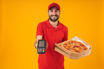 Photo of attractive delivery man in red uniform holding pizza box and payment terminal