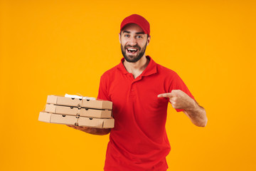 Portrait of attractive delivery man in red uniform smiling and holding pizza boxes