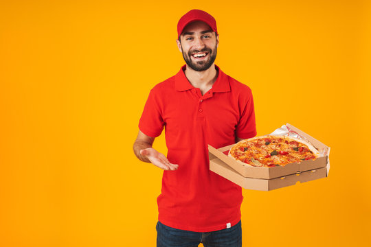 Photo of happy joyful man in red uniform smiling and holding pizza box - Powered by Adobe