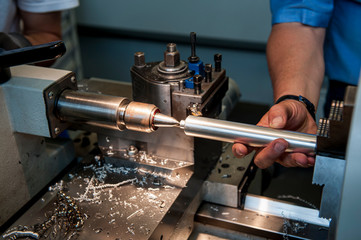 Arbeiter mit Werkstück an der Drehmaschine, Nahaufnahme