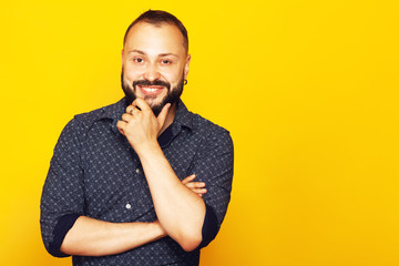 Fabulous at any age. Profile portrait of charismatic 35 years old man standing over yellow background with crossed hands. Short modern haircut. Hipster style. Copy-space. Studio shot