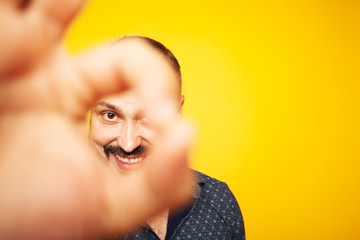 All is OK concept. Close up portrait of charismatic 35 years old man standing over yellow...