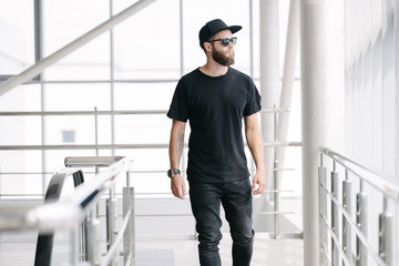 Hipster handsome male model with beard wearing black blank t-shirt with space for your logo or...