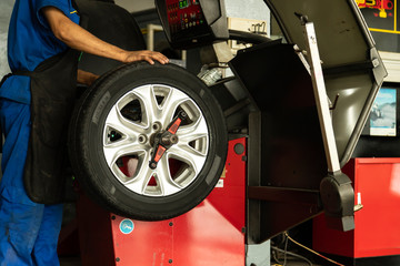 Man worker with Wheel balancing machine for car tire repair service.
