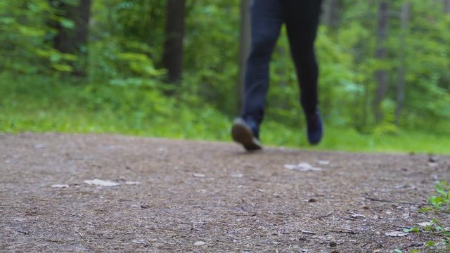 Man runs along the path in the forest. The camera shoots from below.