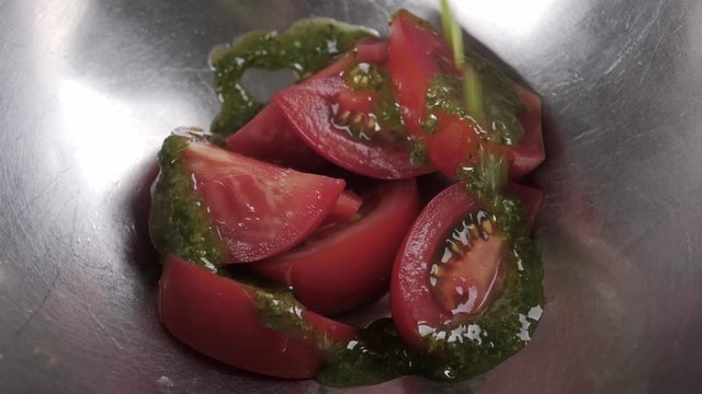 Close up of tomatoes sprinkled with pesto sauce in slow motion. Shef preparing a salad in restaurant. Healthy, tasty food. Diet, holidays, recipe concept.