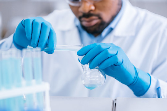 Afro-american scientist works in the lab with different testing tubes.